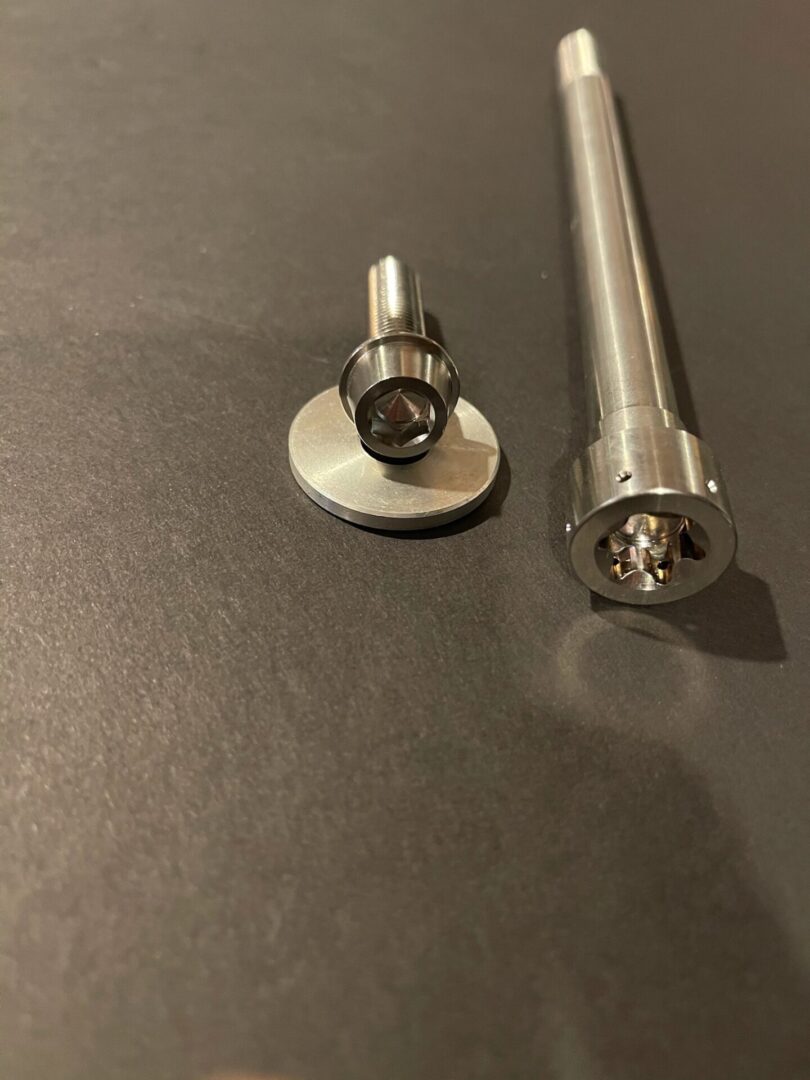 A 22-24 Polaris P22 Titanium Primary Clutch Bolt and a piece of metal on a table.