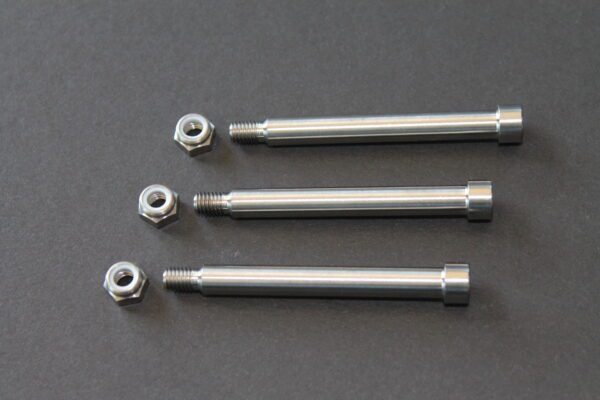 Four stainless steel bolts and nuts on a gray surface.